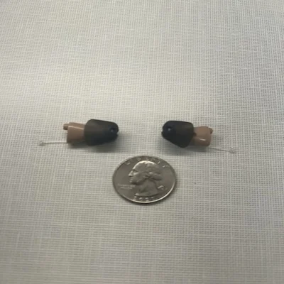 The MDHearing NEO XS hearing aids next to a quarter.