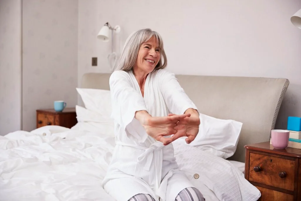 senior woman waking up and stretching in bedroom