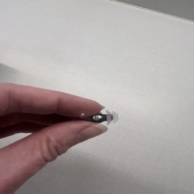 The Eargo 7 hearing aid held by a woman’s fingertips.
