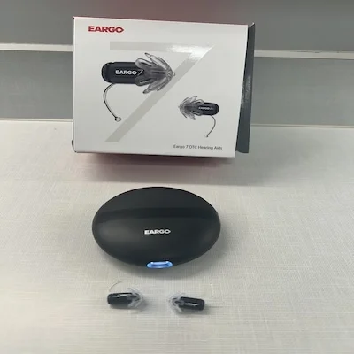 The Eargo 7 hearing aids, charging case, and outer packaging laid out on a counter.