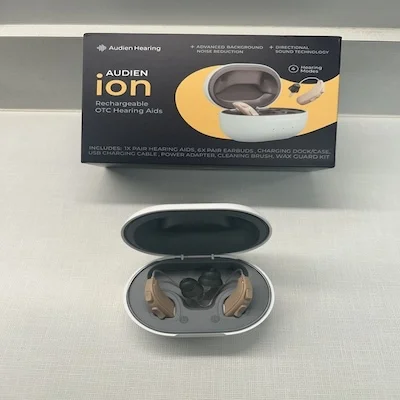 The Audien Ion in its charging case next to the outer packaging.