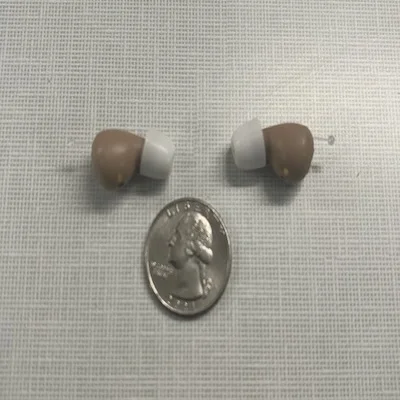 Audien Atom Pro 2 hearing aids compared to the size of a quarter