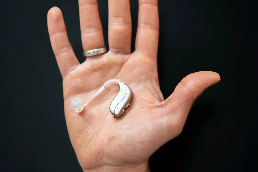 A hearing aid sitting in the palm of someone's hand