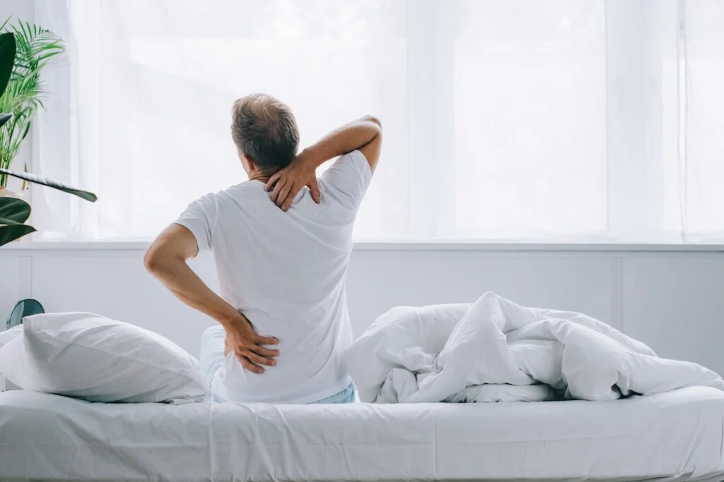 back view of man sitting on bed and suffering