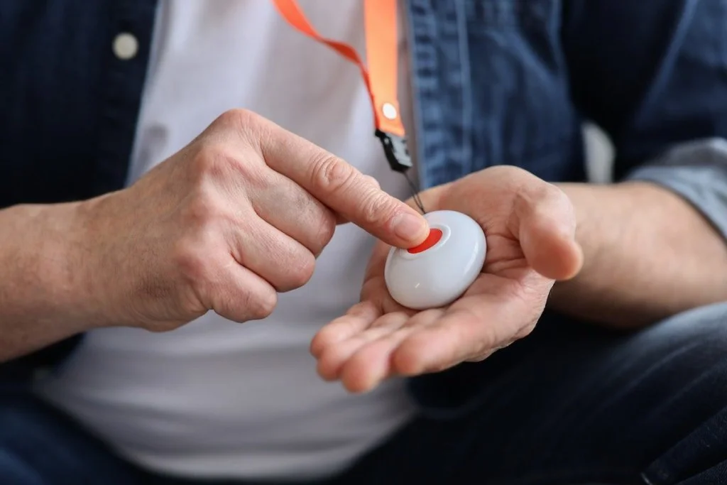 Unrecognizable senior man pushing panic button on emergency equipment for elderly people, cropped. Closeup of man's hand pressing alarm button for emergency hung on his chest