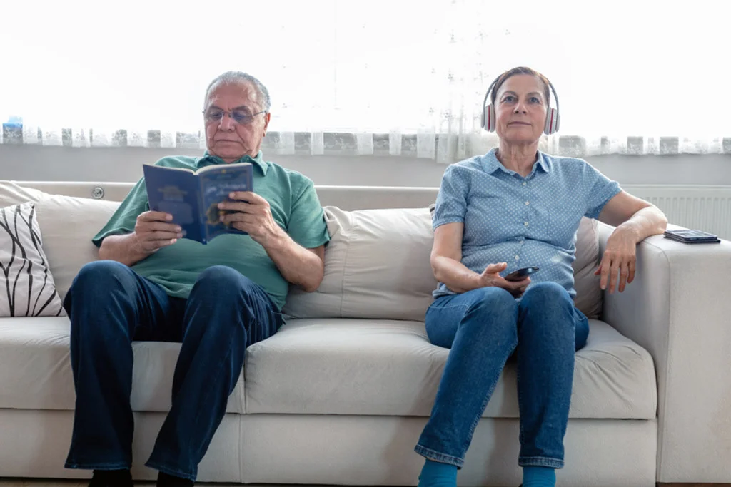 Man reading book while elderly listening beside him
