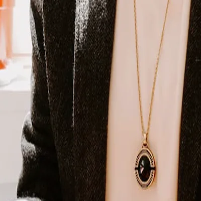 A black and gold necklace rests on a woman’s chest