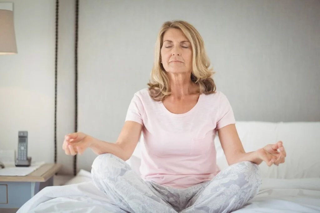 senior practicing yoga on bed