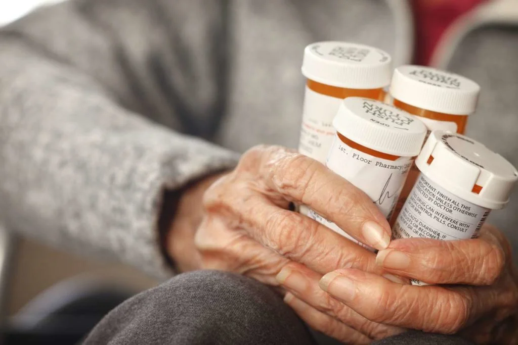 older woman holding medication bottles