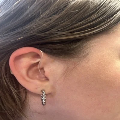 Woman with a pierced ear wears a behind-the-ear hearing aid in her right ear