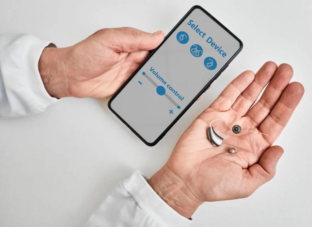 A person holding a hearing aid and pairing it to their phone